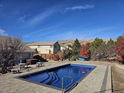 An inground swimming pool near Sparks Nevada in a residential home surrounded by a gate and mountains in the background.